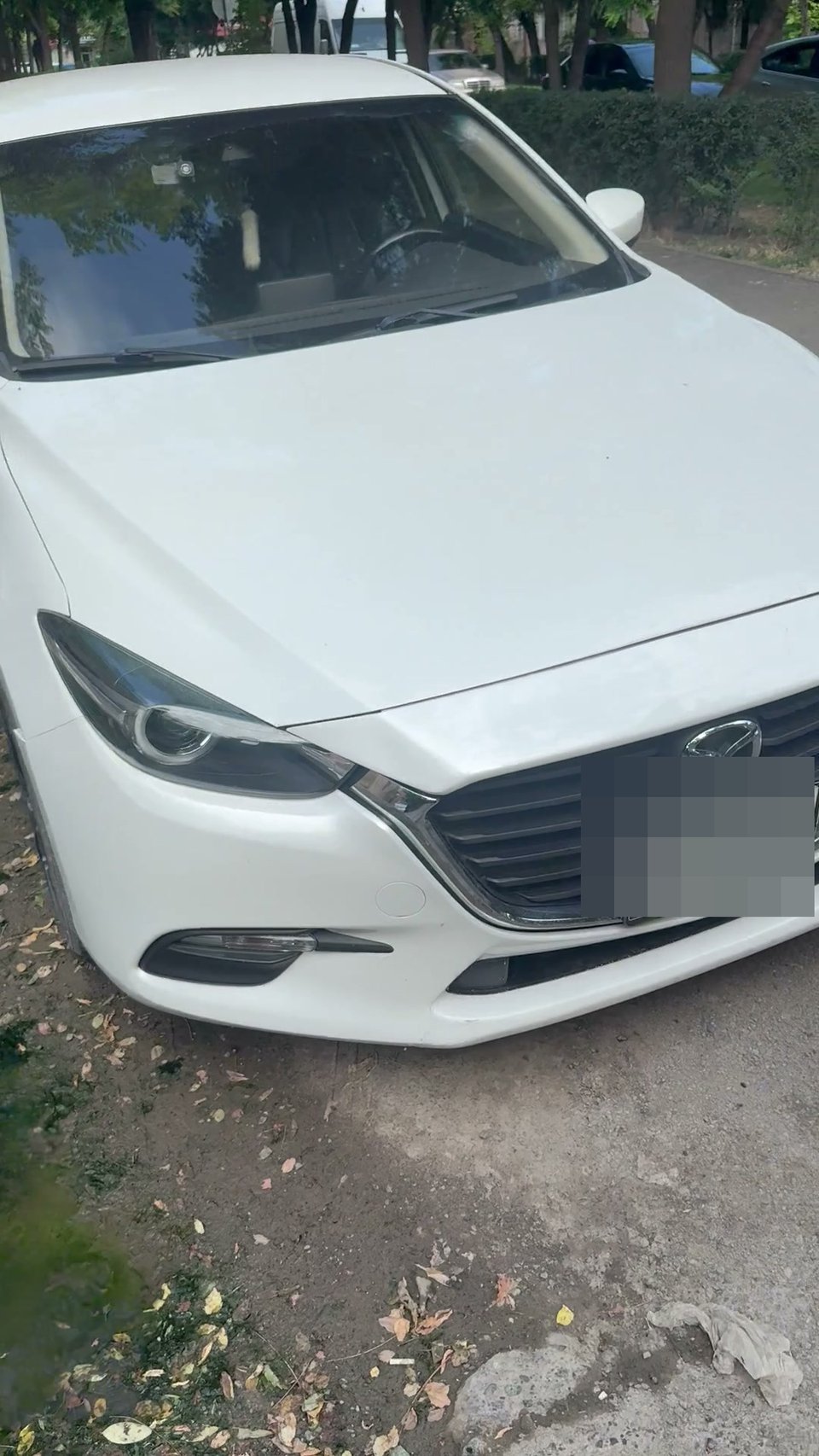 A car parked on a dirt strip in a courtyard, not clearly a public sidewalk